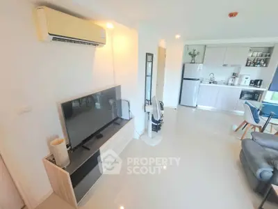 Modern open-plan living room with kitchen, featuring sleek appliances and stylish decor.