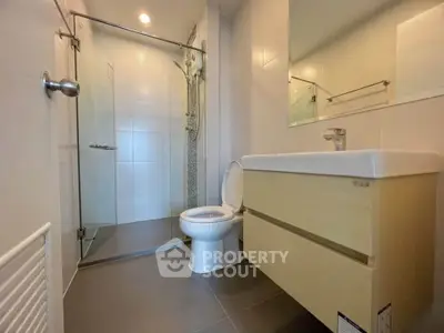 Modern bathroom with glass shower and sleek vanity in a contemporary home.