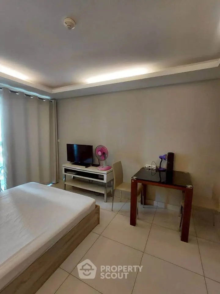 Modern bedroom with minimalist decor, featuring a bed, TV, and small dining area, perfect for urban living.