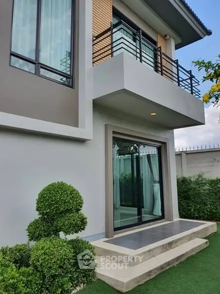 Modern two-story house with balcony and landscaped garden