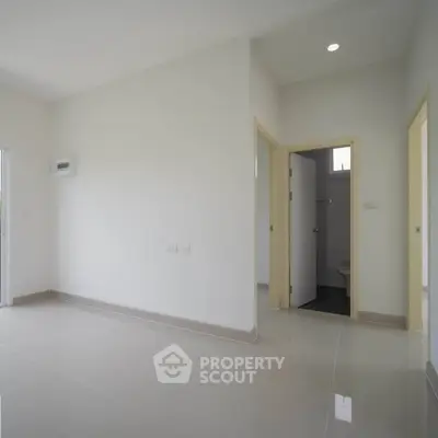 Spacious empty room with glossy tiled floor and two doorways, ideal for customization.