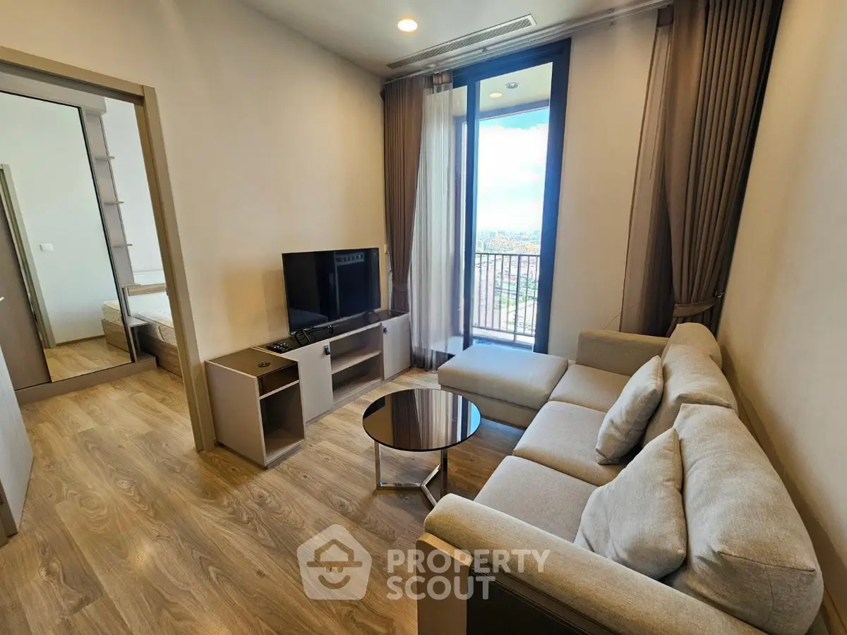 Modern living room with cozy sofa and TV, featuring a view of the city through large windows.