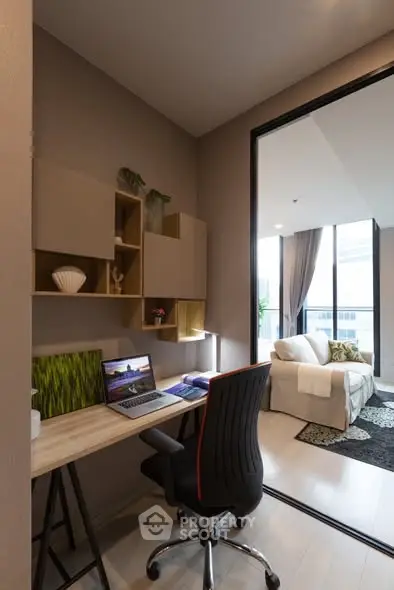 Modern study area with desk and chair adjacent to a cozy living room with large windows.