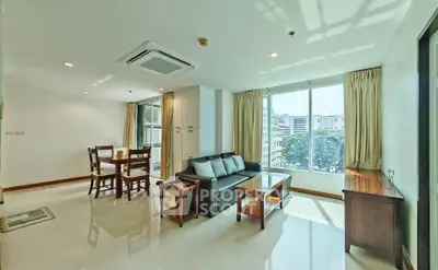 Spacious living room with modern furniture and large windows offering city views.