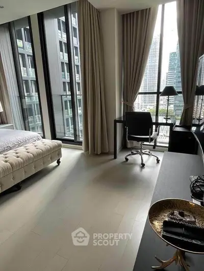 Luxurious bedroom with floor-to-ceiling windows and city view, featuring elegant decor and a stylish workspace.