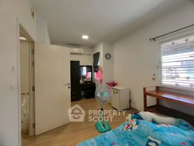 Cozy bedroom with modern decor and natural light, featuring a small fridge and air conditioning.