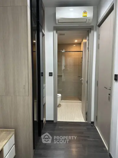 Modern apartment hallway leading to a sleek bathroom with glass shower enclosure.