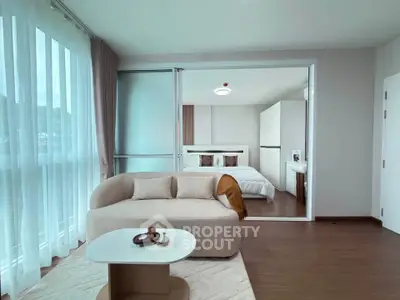 Modern open-plan living room with cozy sofa and elegant bedroom view