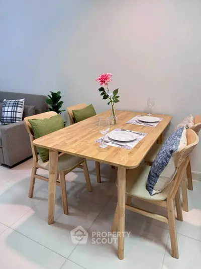 Modern dining area with wooden table and chairs, cozy cushions, and elegant table setting in stylish apartment.