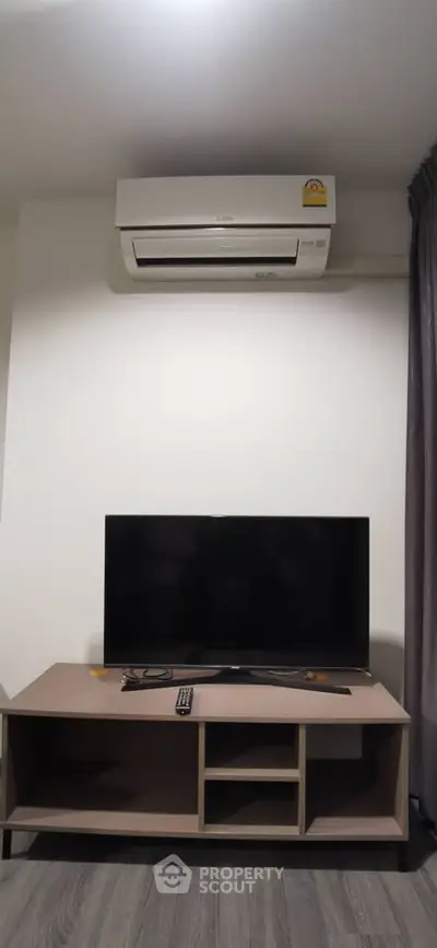 Modern living room with sleek TV setup and air conditioning unit, perfect for comfortable living.