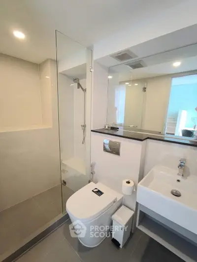 Modern bathroom with sleek design, featuring glass shower and contemporary fixtures.