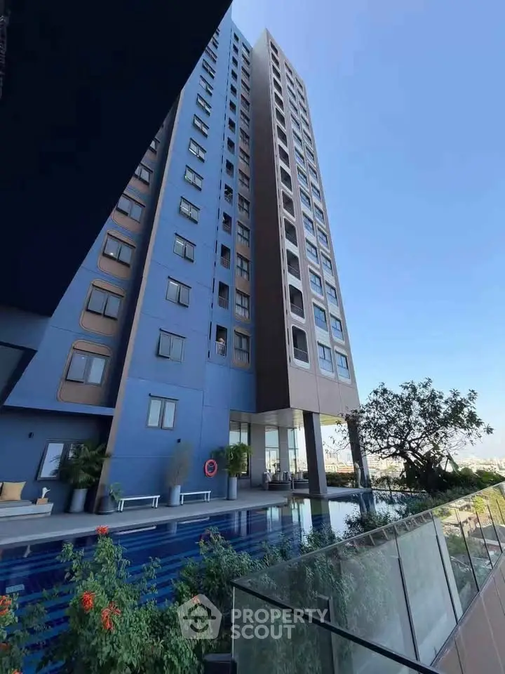 Modern high-rise building with pool and garden, offering luxurious urban living.