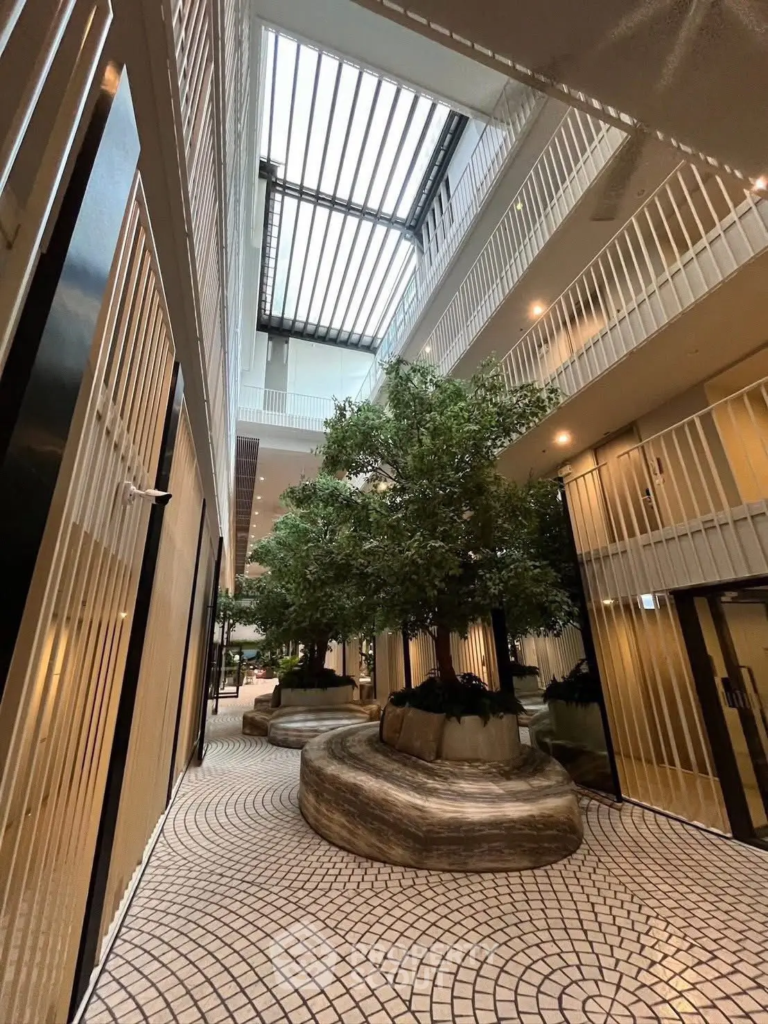Stunning modern building interior with skylight and lush greenery, perfect for luxury living.