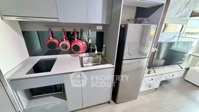 Modern kitchen with sleek cabinetry, induction cooktop, and stainless steel fridge in a stylish apartment.