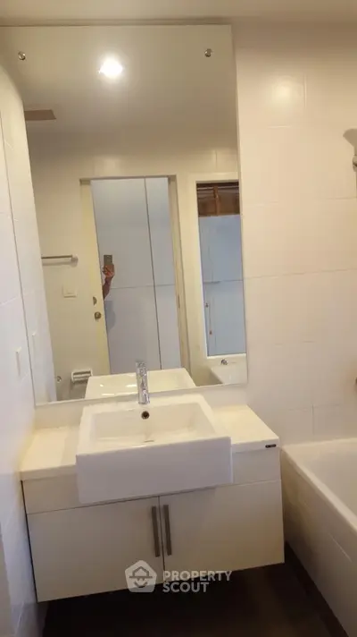 Modern bathroom with sleek white fixtures and large mirror