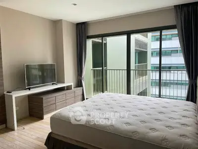 Modern bedroom with large window and TV, featuring a comfortable bed and sleek furniture.