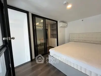 Modern bedroom with sleek design, featuring a large bed, built-in wardrobe, and air conditioning.