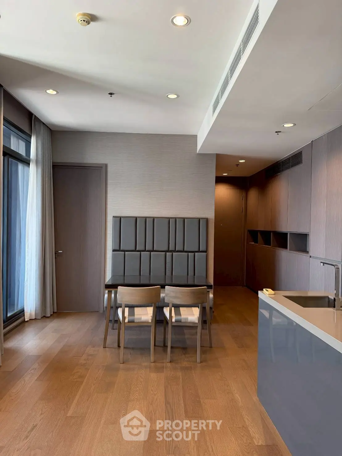 Modern dining area with sleek wooden flooring and contemporary furniture in a stylish apartment.