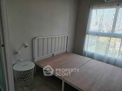 Cozy bedroom with natural light and minimalist decor, featuring a bed frame and side table.