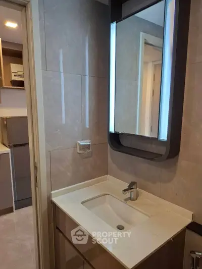 Modern bathroom with sleek sink and illuminated mirror in stylish apartment.