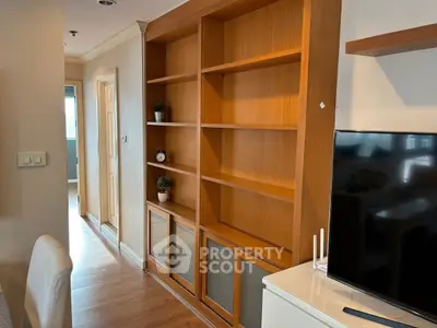 Spacious living room with wooden shelves and modern TV setup, perfect for entertainment and relaxation.