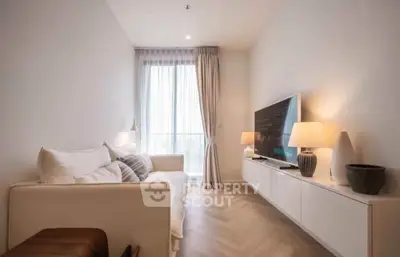 Modern living room with cozy sofa and large TV, featuring elegant lighting and natural light from a large window.