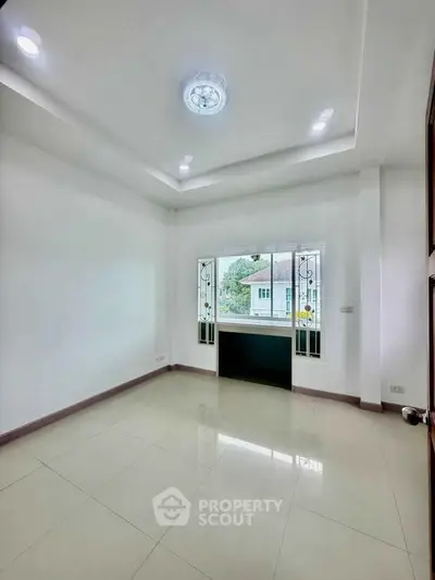 Spacious empty room with large window and modern ceiling lights, perfect for customization.