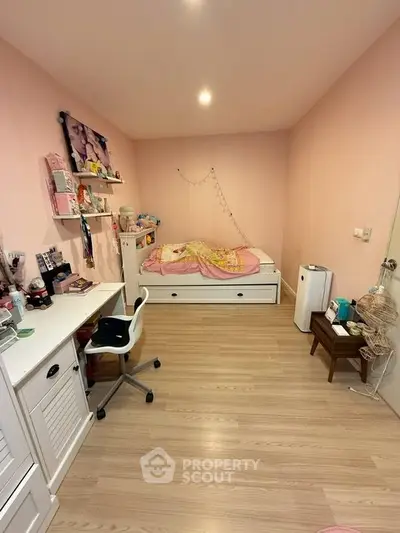 Charming bedroom with pink walls, cozy bed, and stylish desk, perfect for a child's dream space.