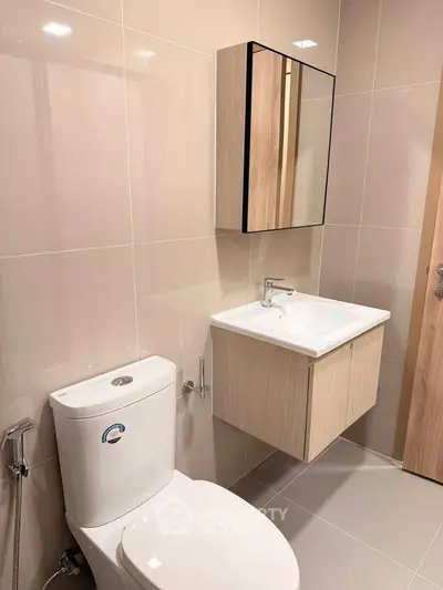 Modern bathroom with sleek fixtures and neutral tiles, featuring a wall-mounted sink and toilet.
