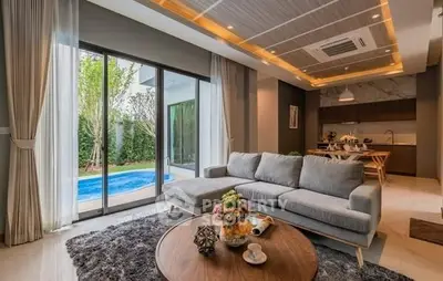 Luxurious living room with pool view, modern decor, and open kitchen layout.