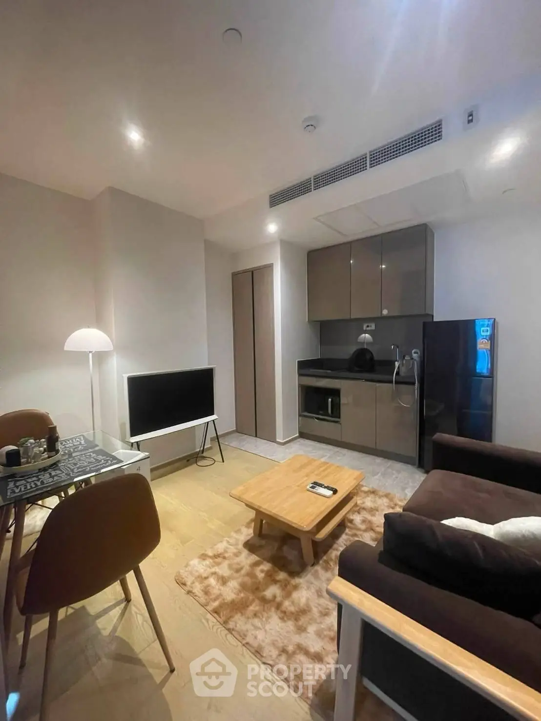 Modern living room with cozy seating and sleek kitchen in open layout apartment.