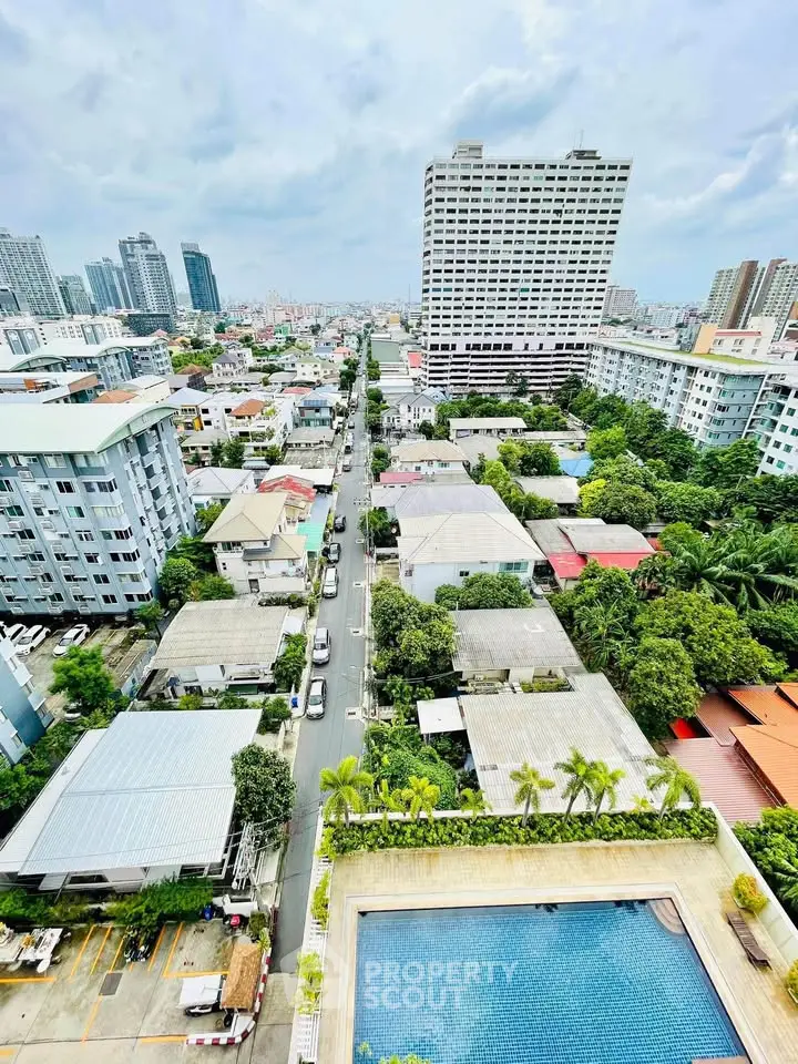 Stunning aerial view of urban landscape with high-rise buildings and lush greenery, featuring a rooftop pool.