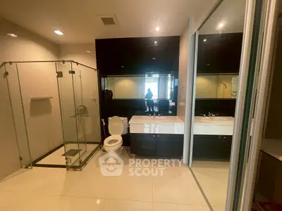 Luxurious modern bathroom with glass shower and sleek black accents.