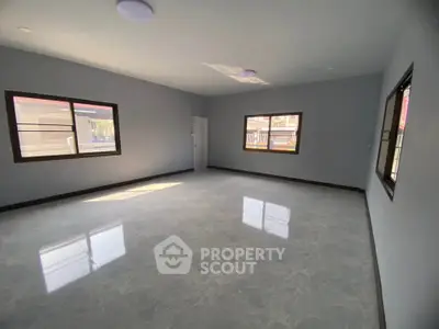Spacious empty room with large windows and polished floors, perfect for customization.