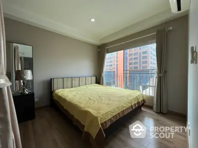 Modern bedroom with large window and city view, featuring elegant decor and natural light.