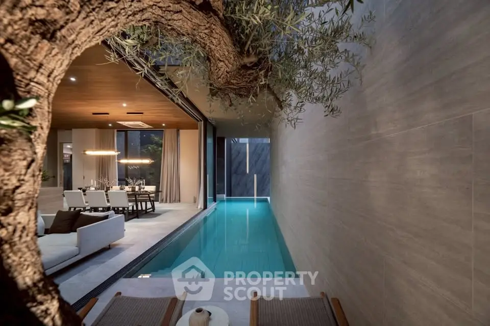 Luxurious indoor pool with elegant dining and living area, featuring modern design and ambient lighting.