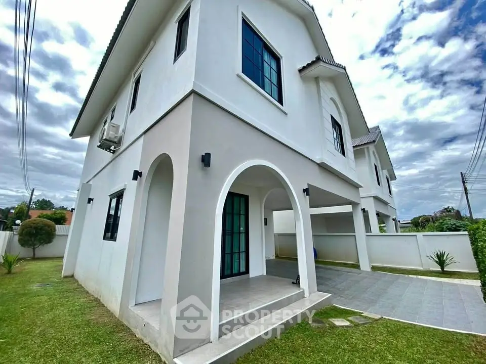 Elegant two-story house with arched entrance and spacious driveway in a serene neighborhood.