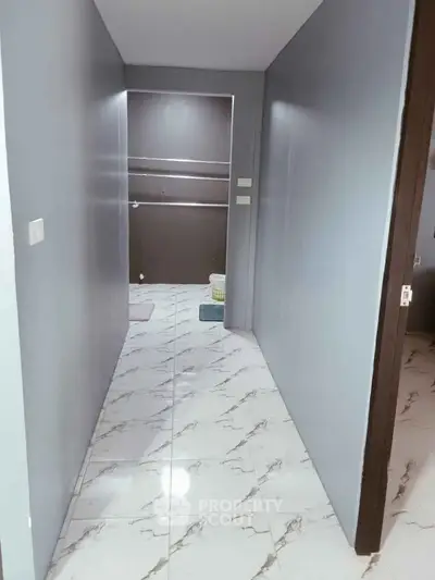 Modern hallway with marble flooring leading to a bathroom