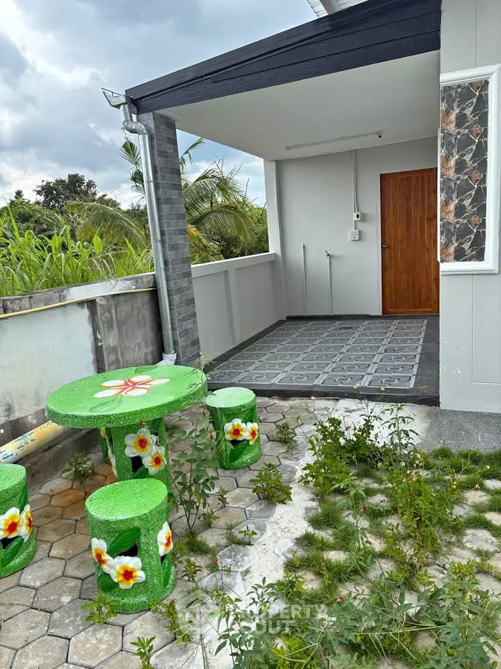 Charming outdoor patio with vibrant green furniture and lush garden view