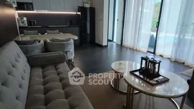 Luxurious modern living room with open kitchen and pool view, featuring elegant furniture and natural light.
