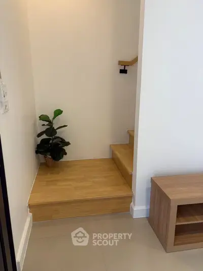 Modern interior with wooden staircase and potted plant, showcasing minimalist design.