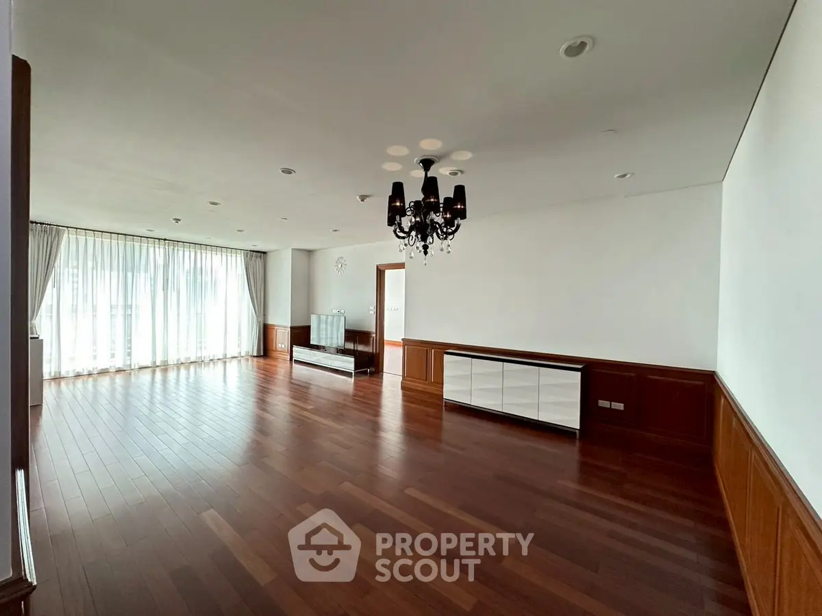 Spacious living room with elegant chandelier and hardwood flooring