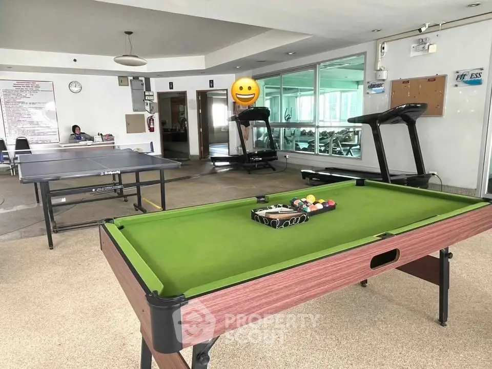 Spacious gym with pool table and treadmills in modern residential building.