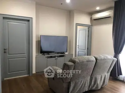 Cozy living room with plush sofa, modern TV setup, and elegant curtains for a comfortable home ambiance.