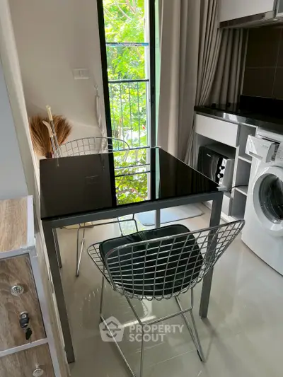 Modern kitchen with sleek black table and chairs, featuring a washing machine and stylish decor.