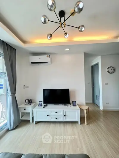 Modern living room with stylish lighting and sleek TV setup in a bright apartment.