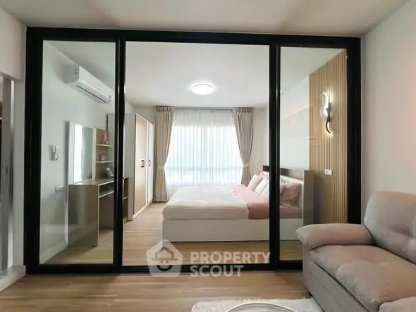 Modern bedroom with glass partition and cozy living area in stylish apartment.