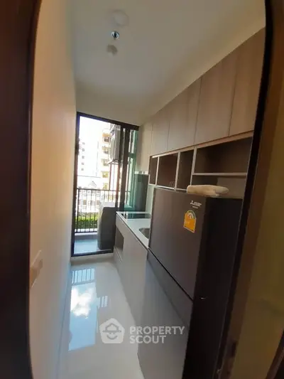 Modern kitchen with sleek appliances and balcony view in a stylish apartment.