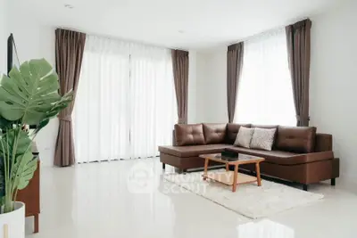 Spacious living room with modern brown leather sofa and large windows