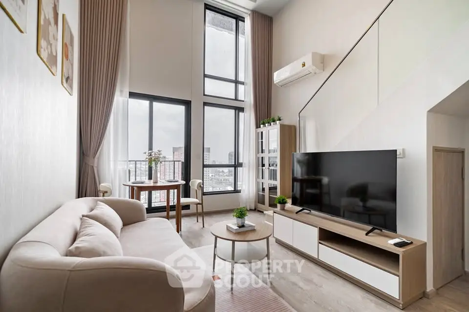 Modern living room with high ceilings, large windows, and stylish furniture in a contemporary apartment.